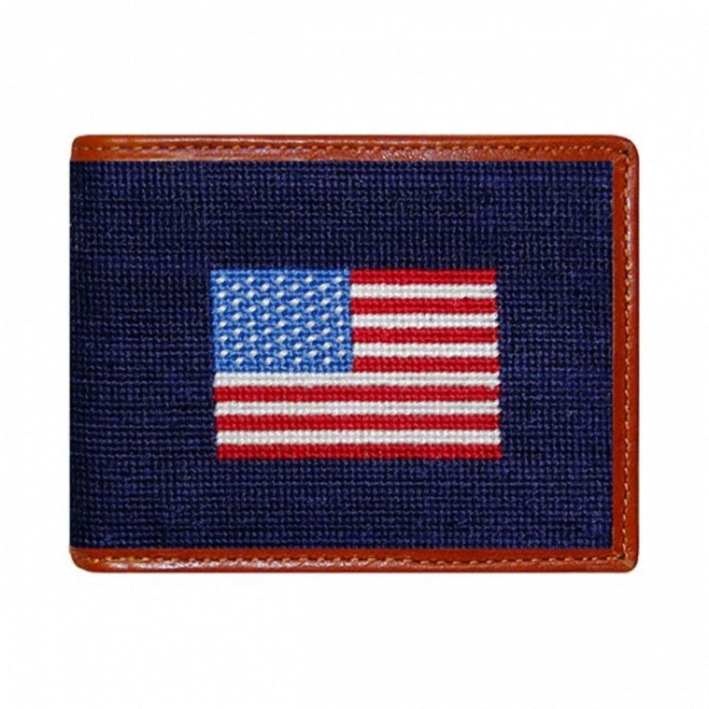 A bi-fold wallet featuring a needlepoint design of the American flag with a brown leather border.