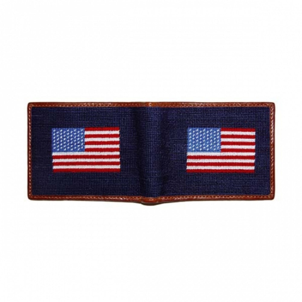 A bi-fold wallet featuring a needlepoint design of the American flag with a brown leather border.